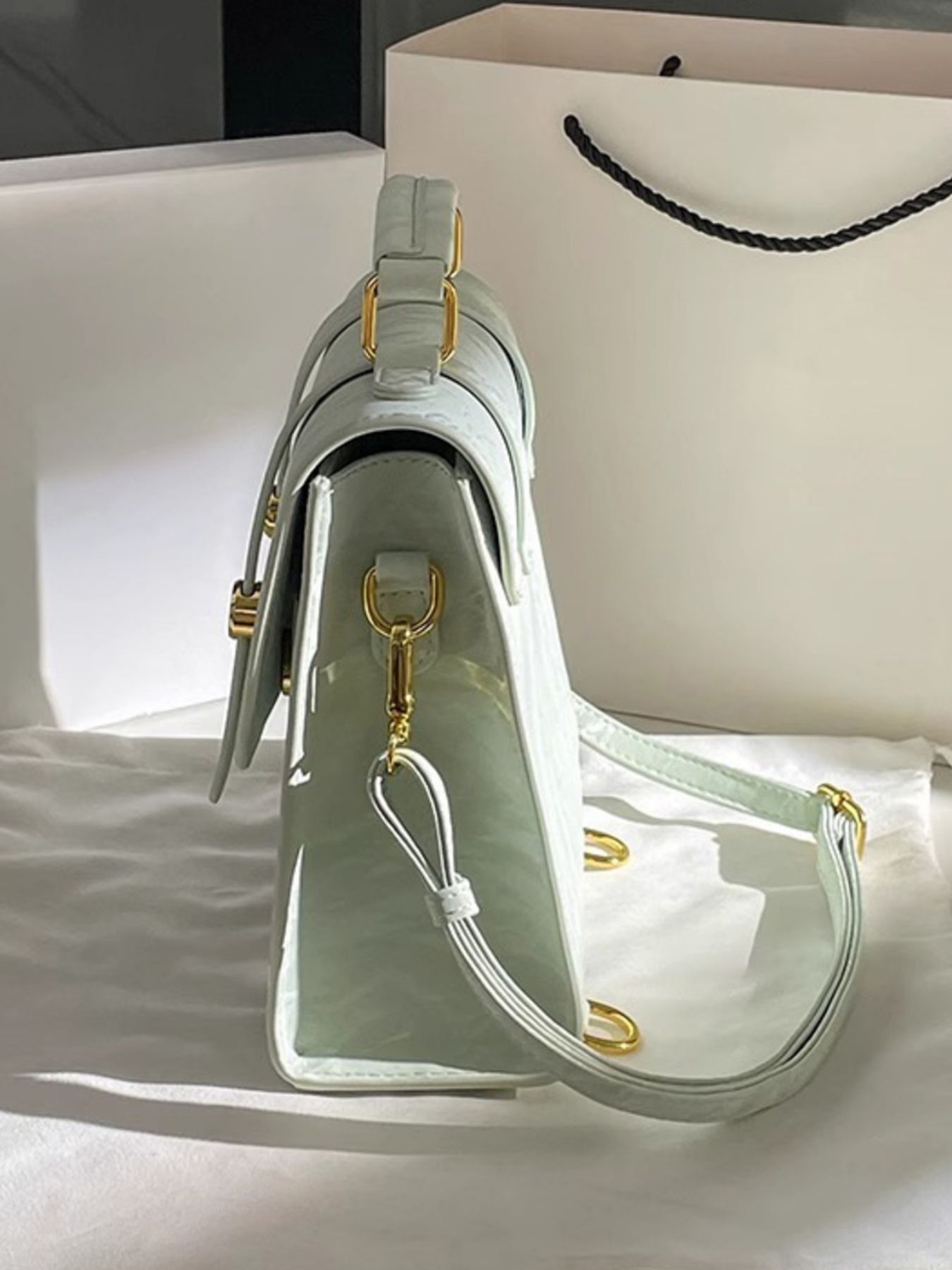 Light green handbag with gold accents on a white surface