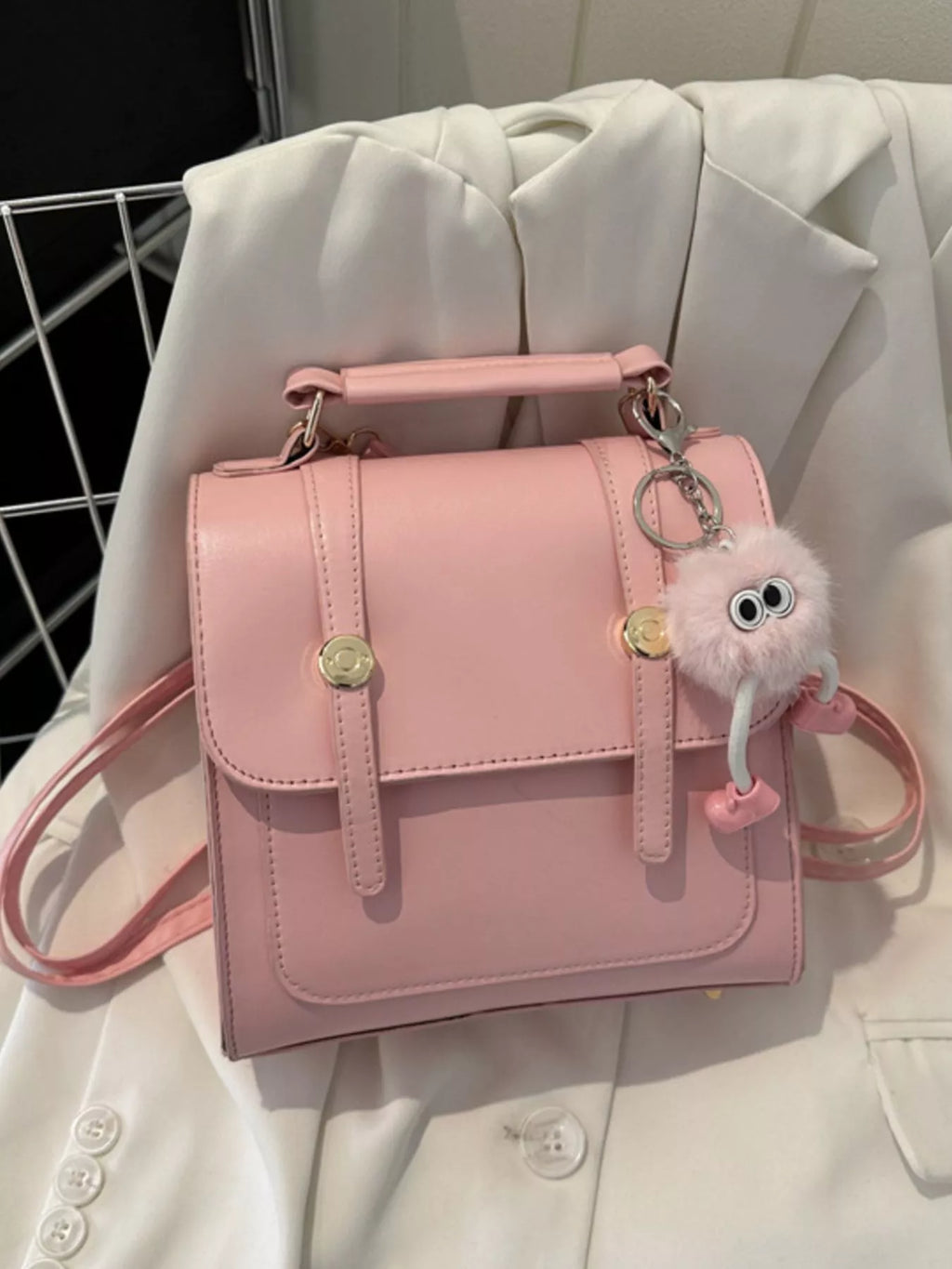 Pink handbag with a keychain on a light-colored fabric background