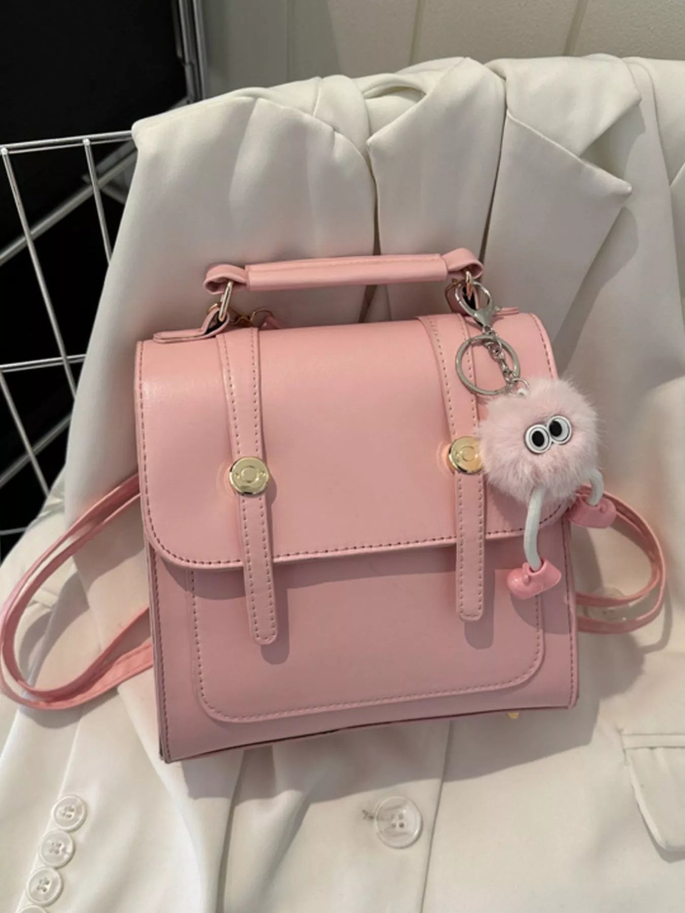 Pink handbag with a keychain on a light-colored fabric background