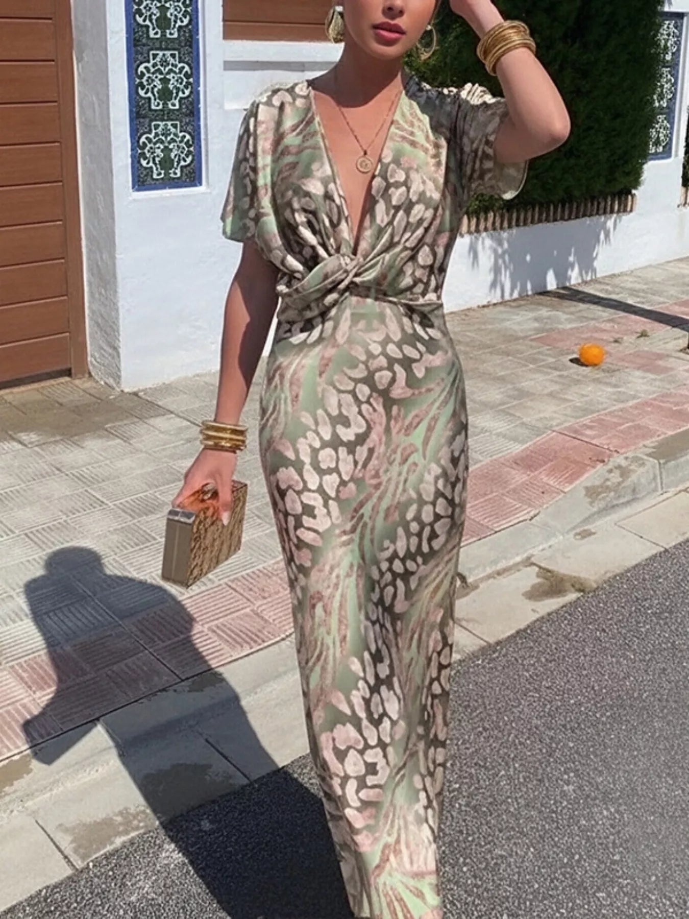 Woman in a patterned dress standing outdoors on a sunny day.