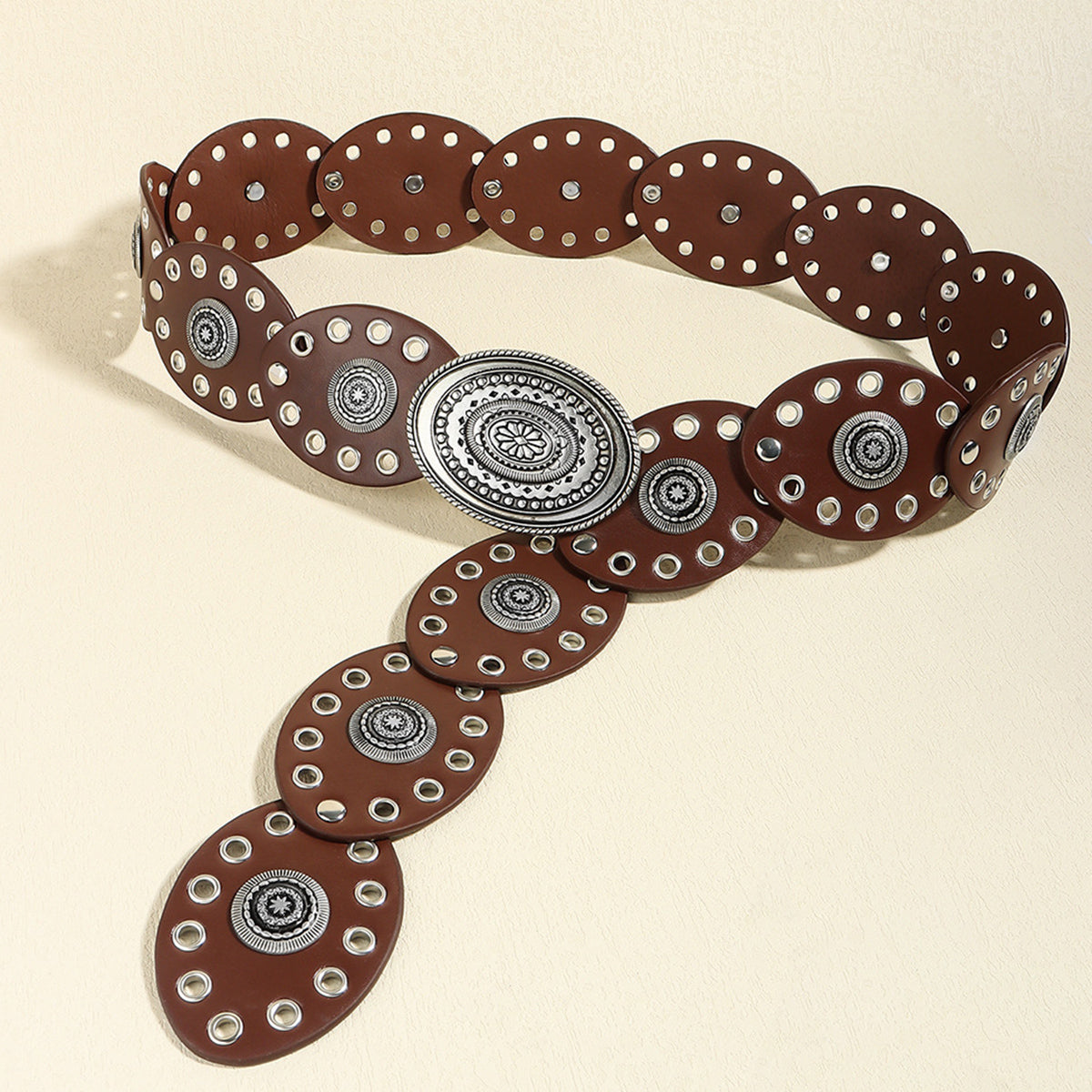 Brown leather belt with silver circular accents on a beige background