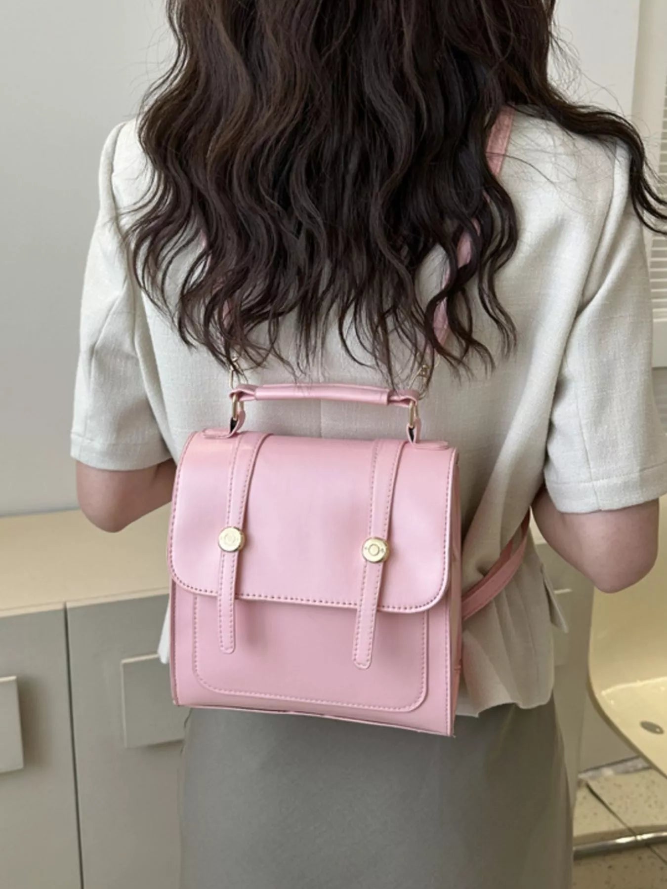 Model wearing a pink crossbody bag in an indoor setting