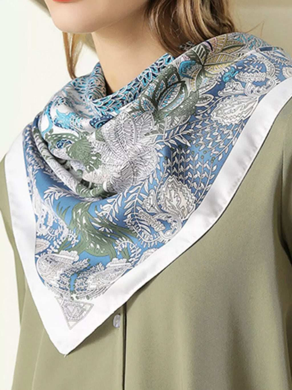 Model wearing a patterned scarf with a green and blue design on a beige background