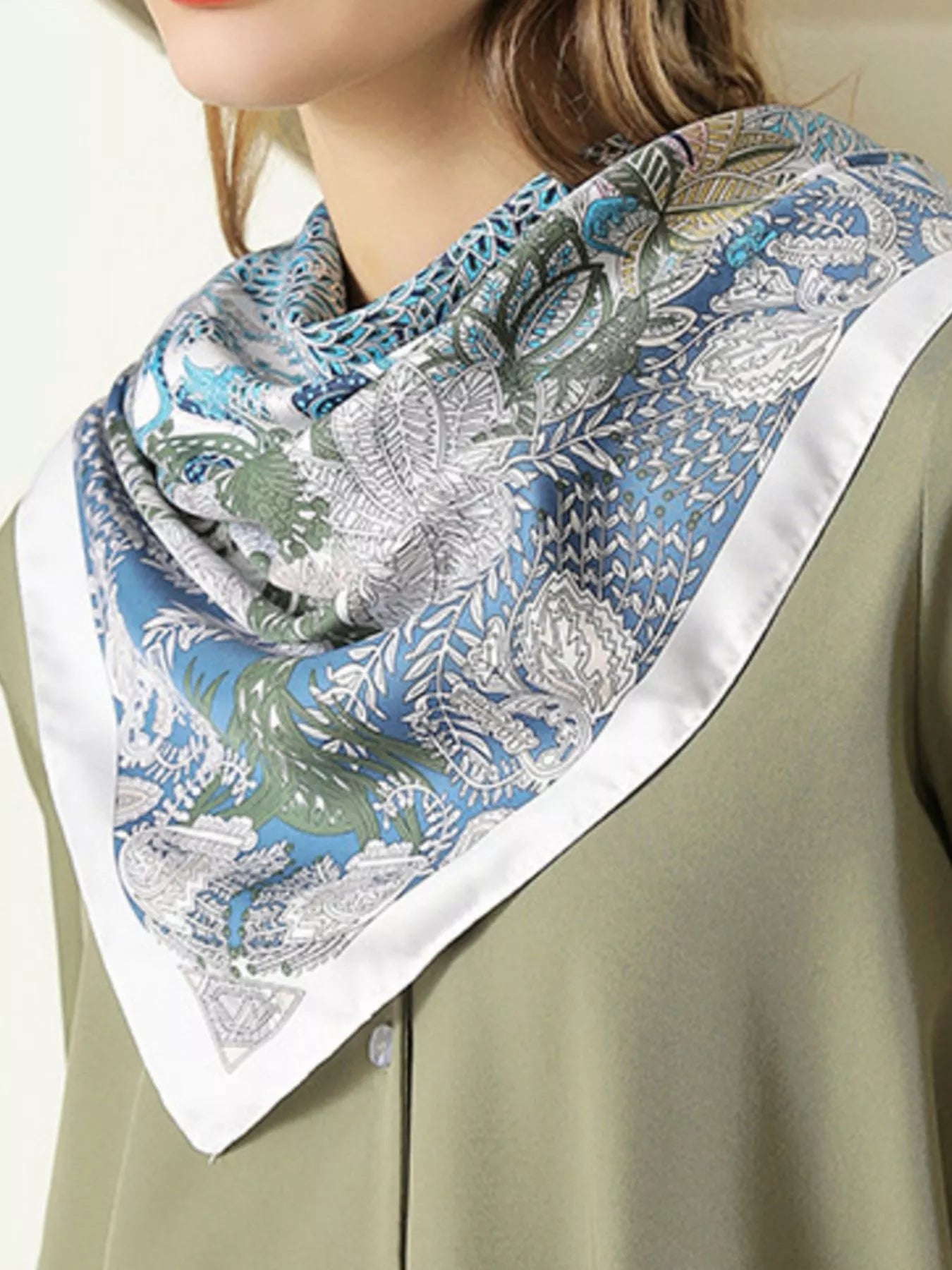 Model wearing a patterned scarf with a green and blue design on a beige background