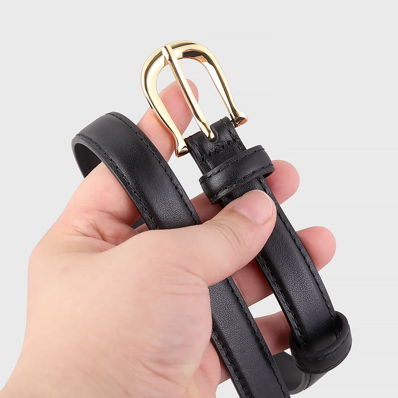 Black leather belt with a gold buckle held by a hand on a light gray background