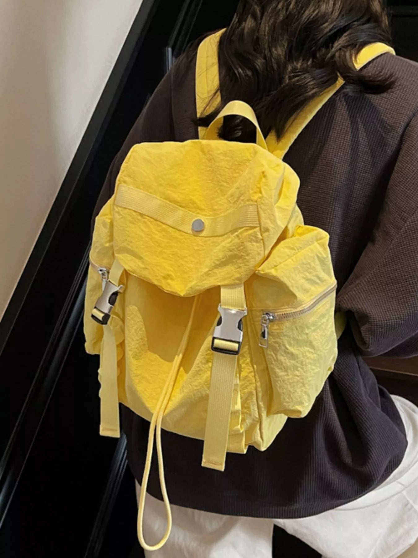 Person wearing a yellow backpack with a neutral background