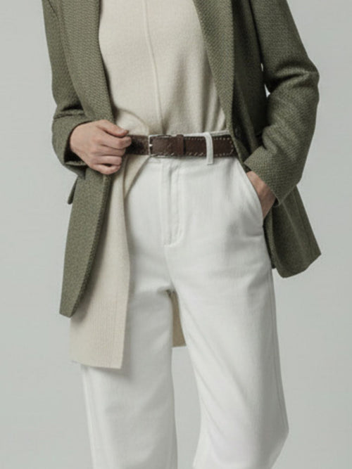 Model wearing a green blazer, beige sweater, and white pants on a plain background