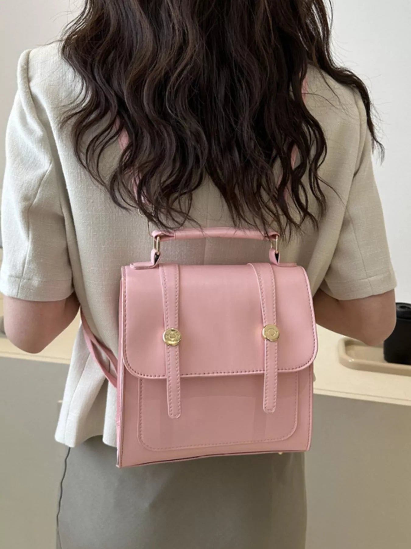 Model wearing a pink backpack with gold accents