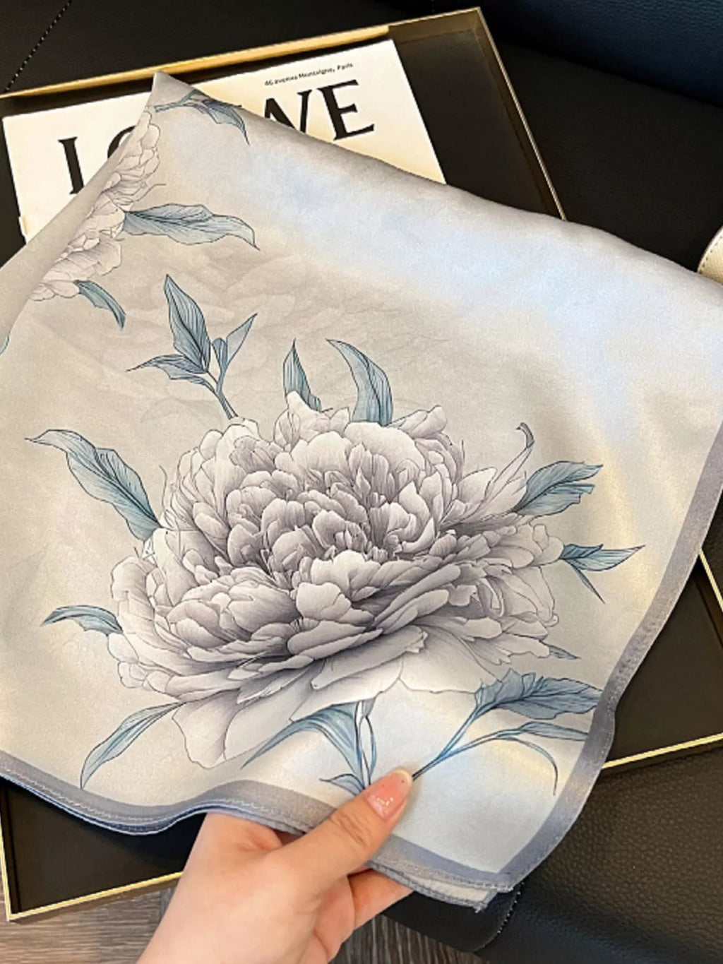 Floral patterned fabric held by a hand on a dark surface