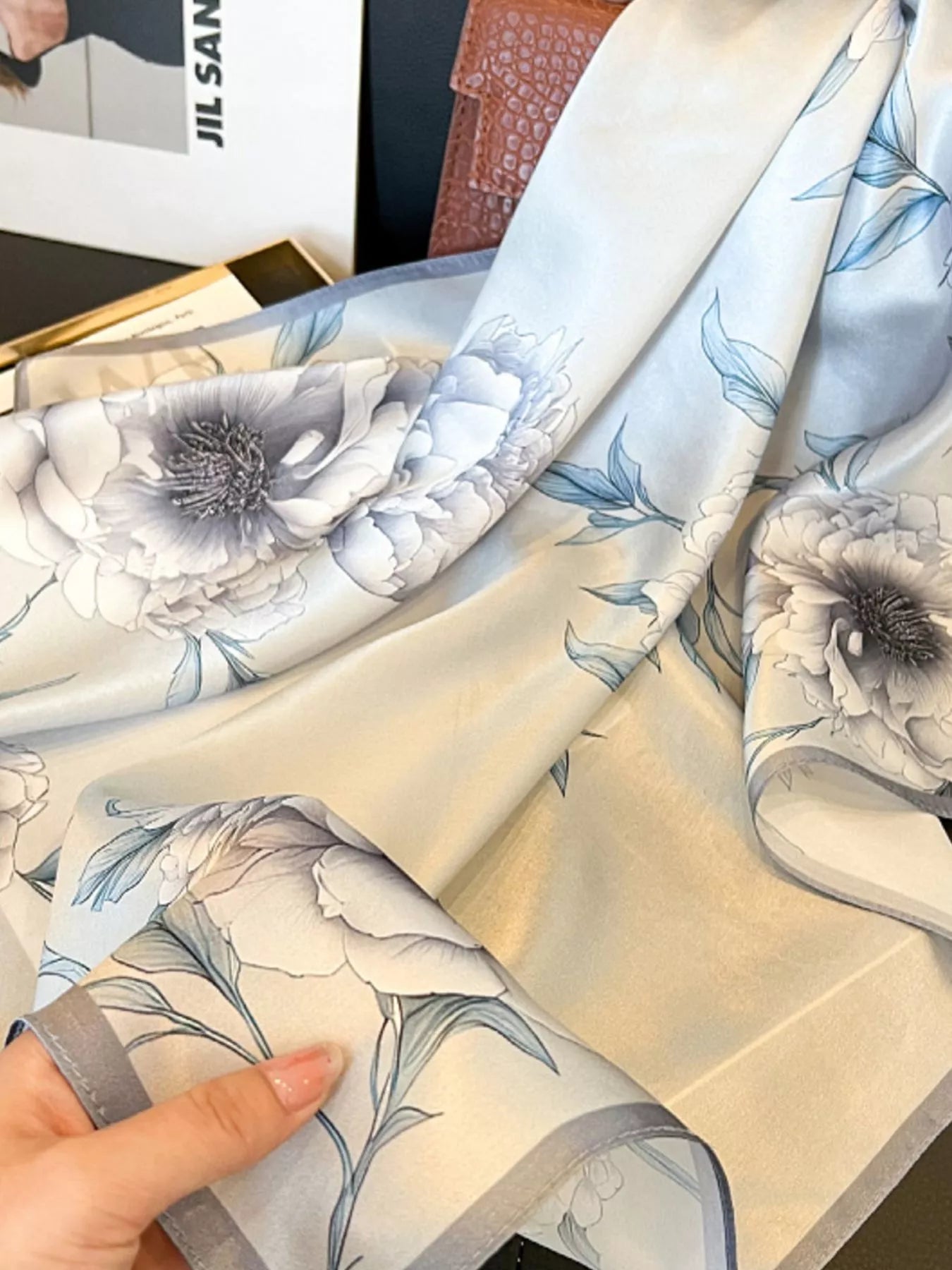 Floral fabric swatch held by a hand with a blurred background