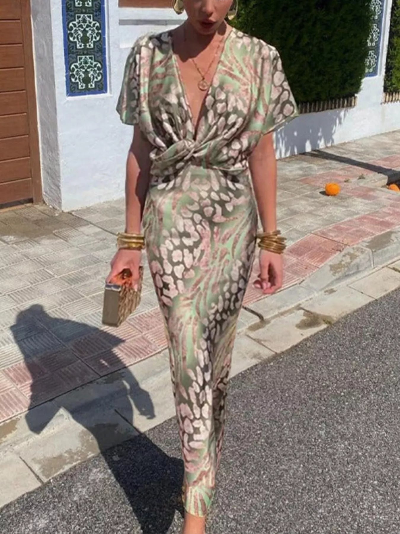 Woman wearing a patterned jumpsuit standing on a street.