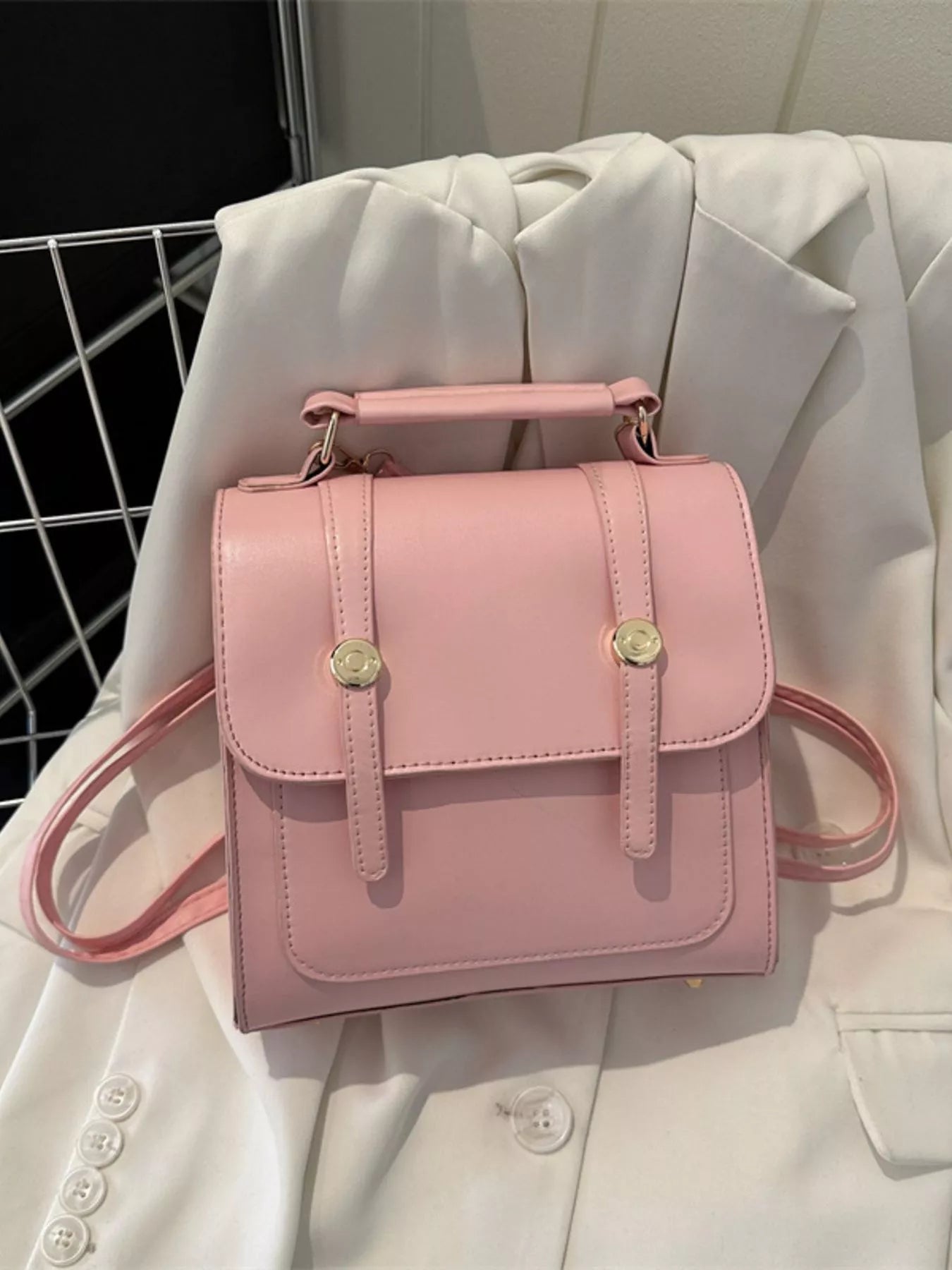 Pink handbag with gold accents on a light-colored fabric background
