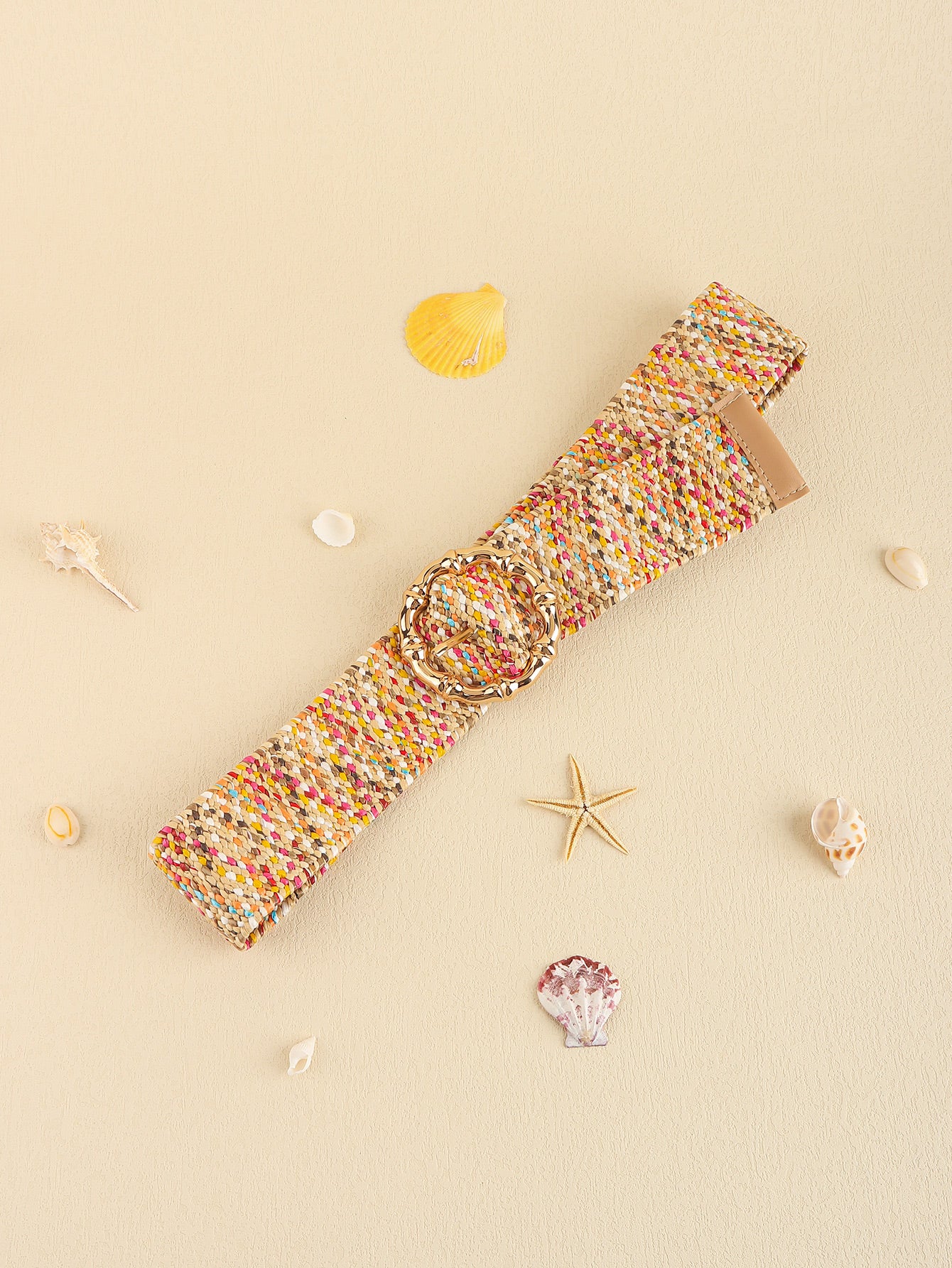 Multicolored woven belt on a beige background with seashells and a starfish.