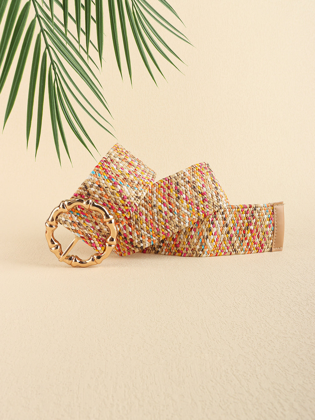 Multicolored woven belt with a gold buckle on a beige background with palm leaves.