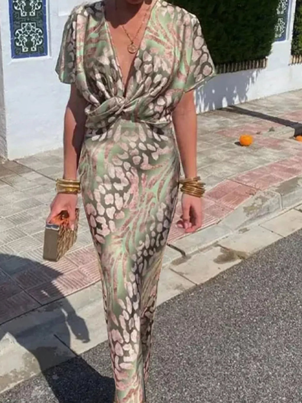 Person wearing a patterned outfit walking on a street.