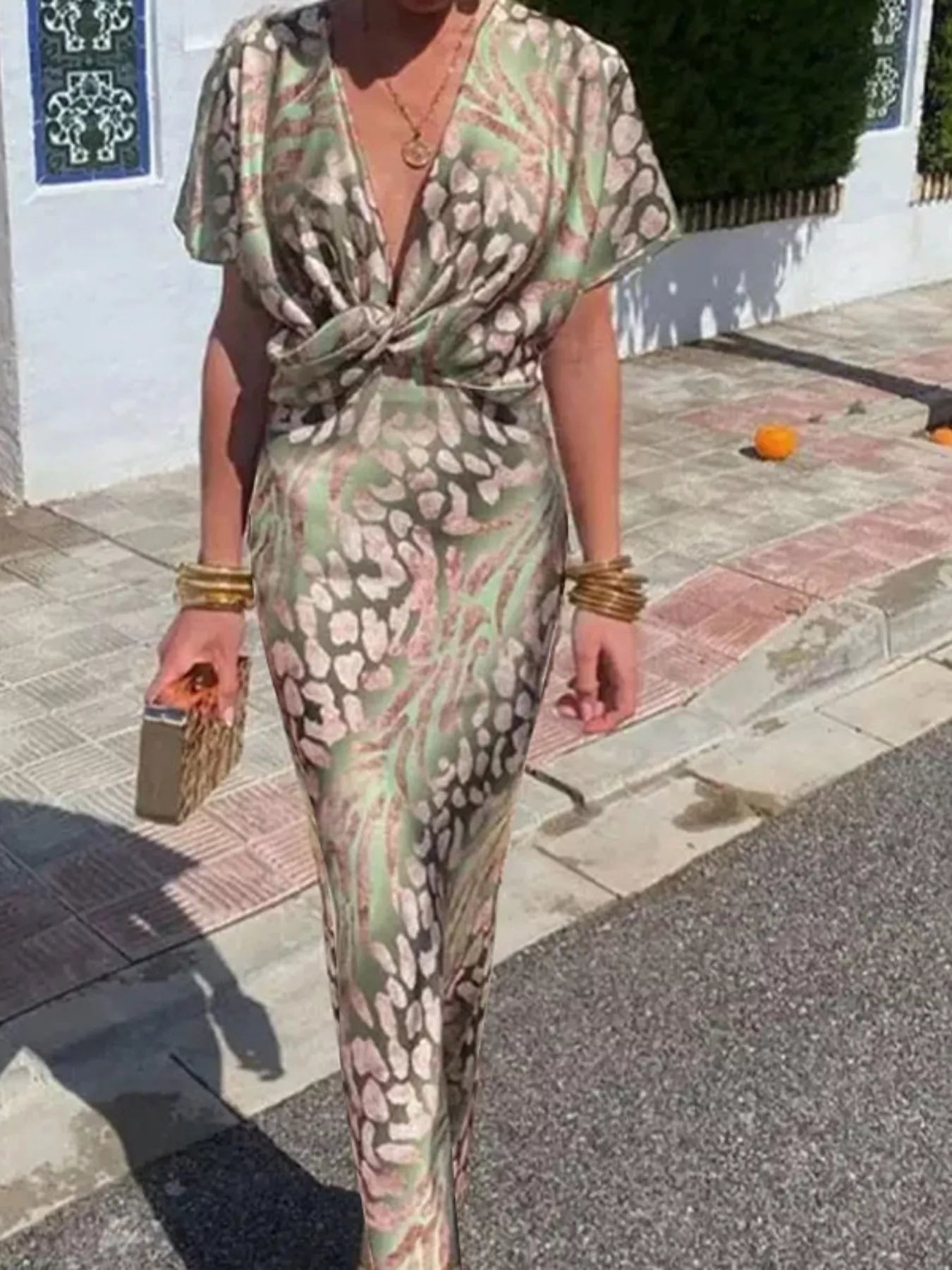 Person wearing a patterned outfit walking on a street.
