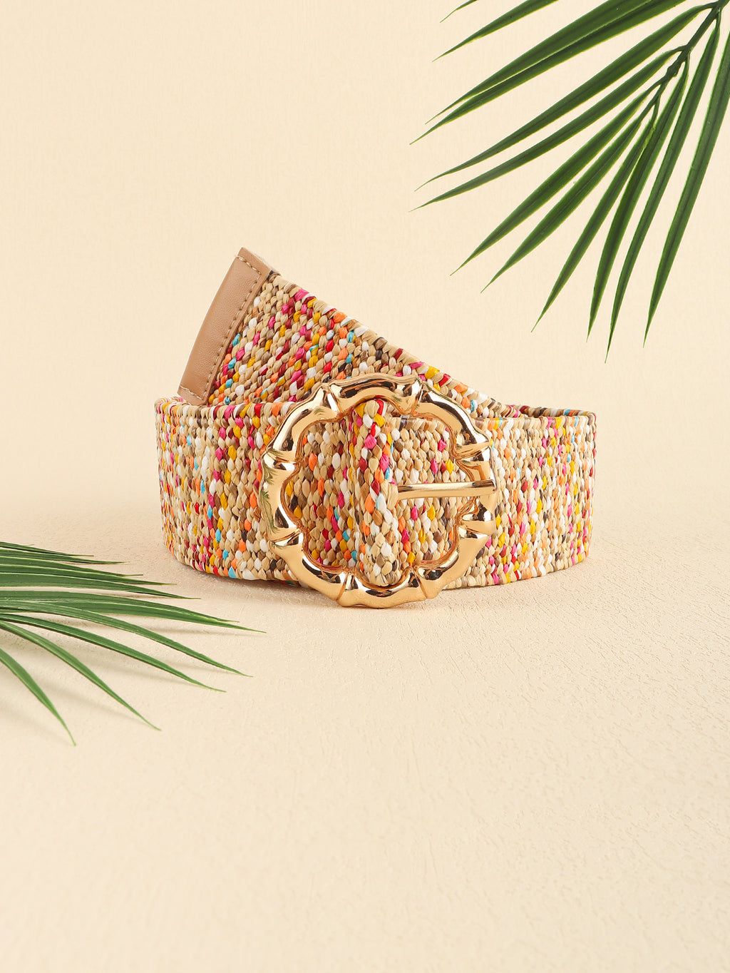 Colorful belt with a gold buckle on a beige background with palm leaves.