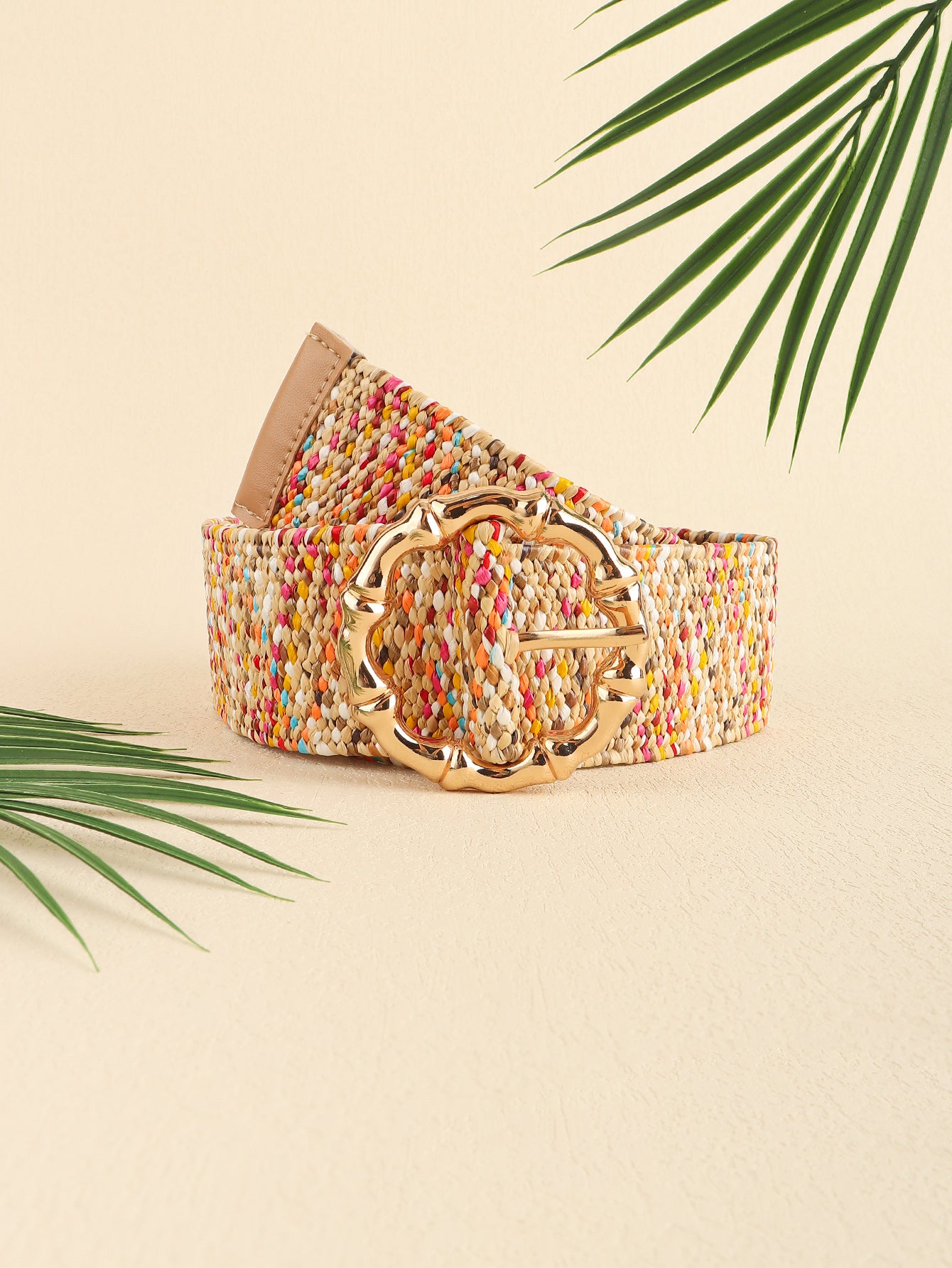 Colorful belt with a gold buckle on a beige background with palm leaves.
