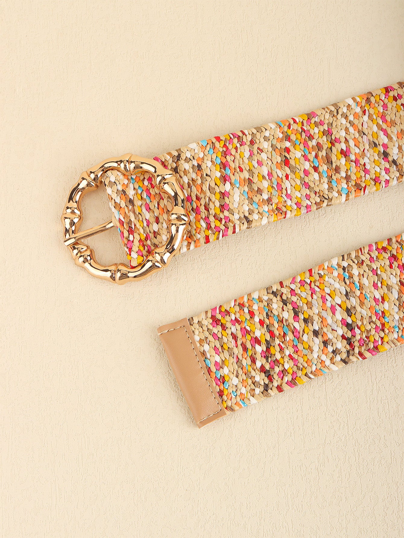 Colorful woven belt with a gold buckle on a beige background