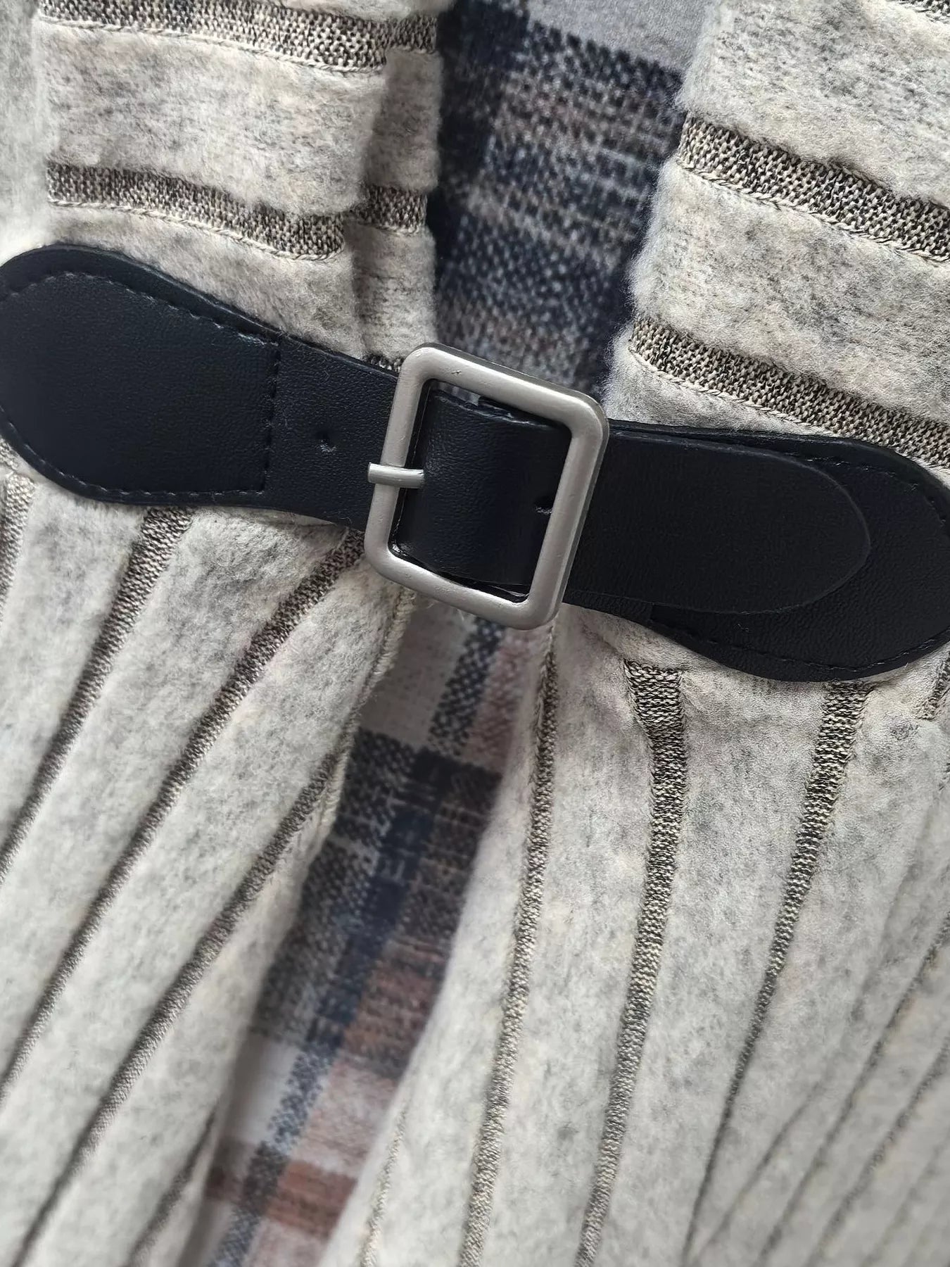 Black leather belt with silver buckle on a textured fabric background