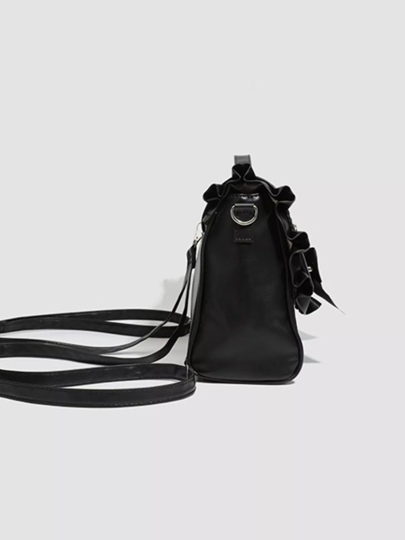 Black handbag with bow details on a light gray background
