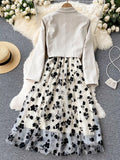 White jacket with long sleeves and a floral skirt on a gray surface with decorative elements.