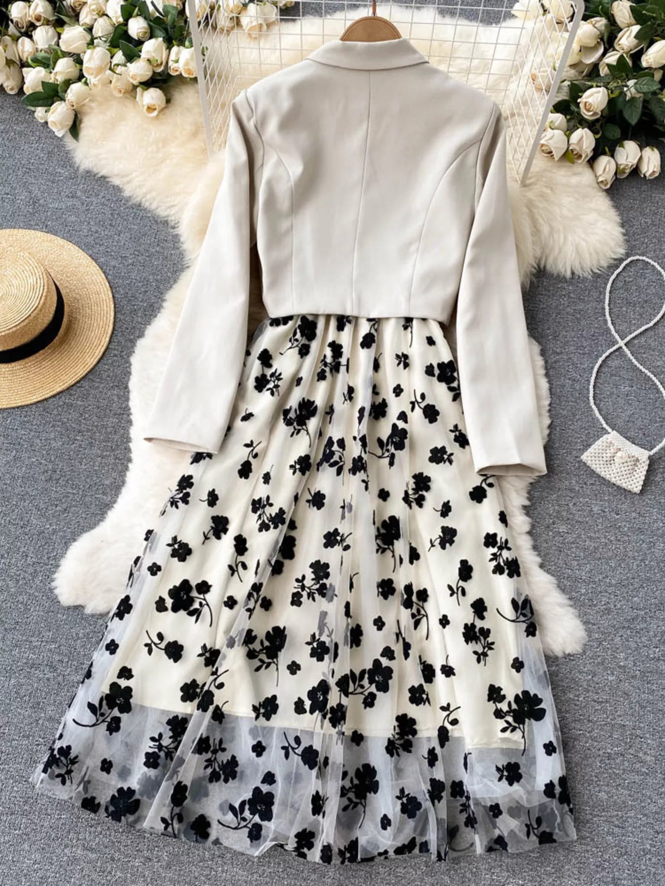 White jacket with long sleeves and a floral skirt on a gray surface with decorative elements.