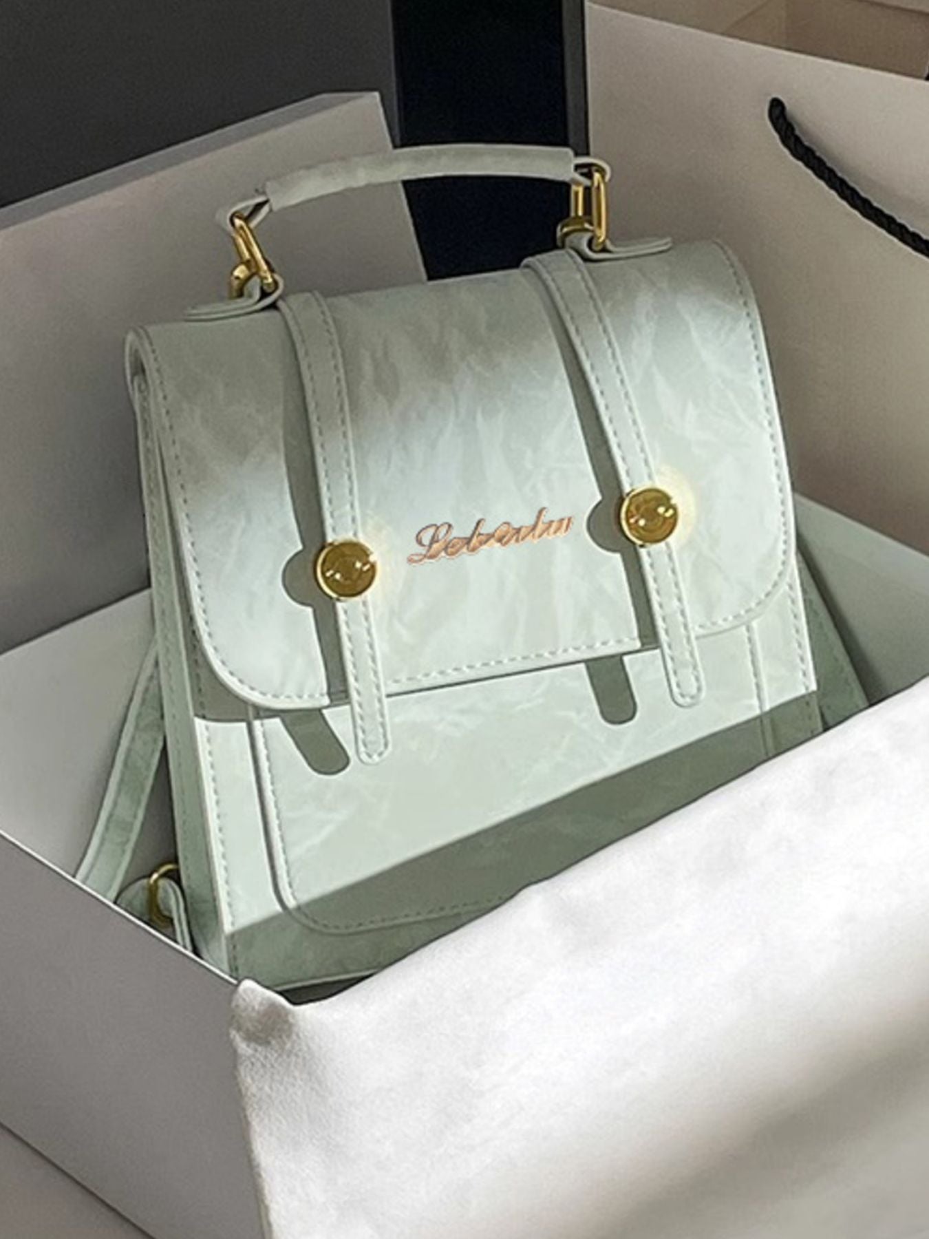 Light green handbag with gold accents on a white surface