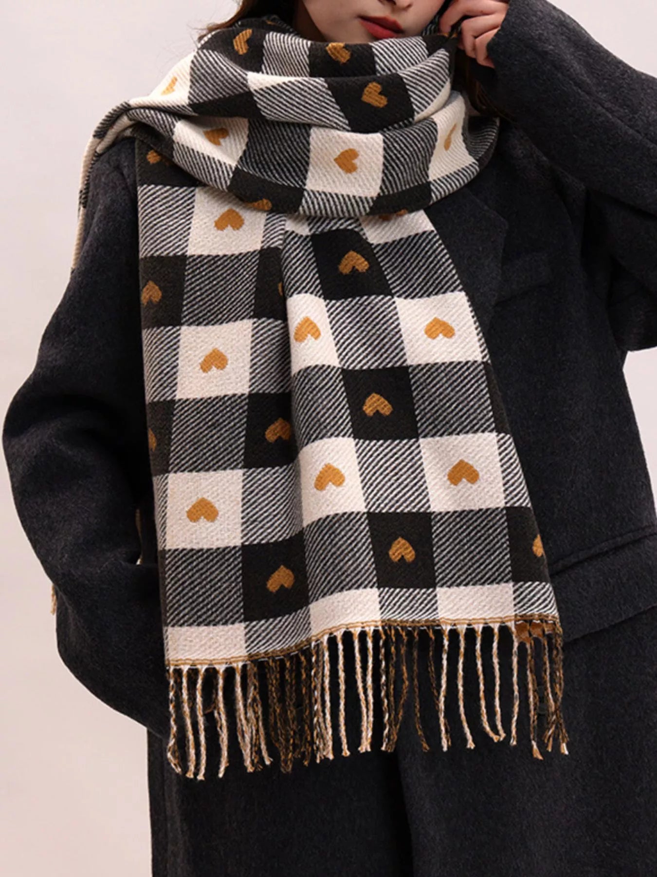 Model wearing a black and white checkered scarf with heart patterns on a plain background