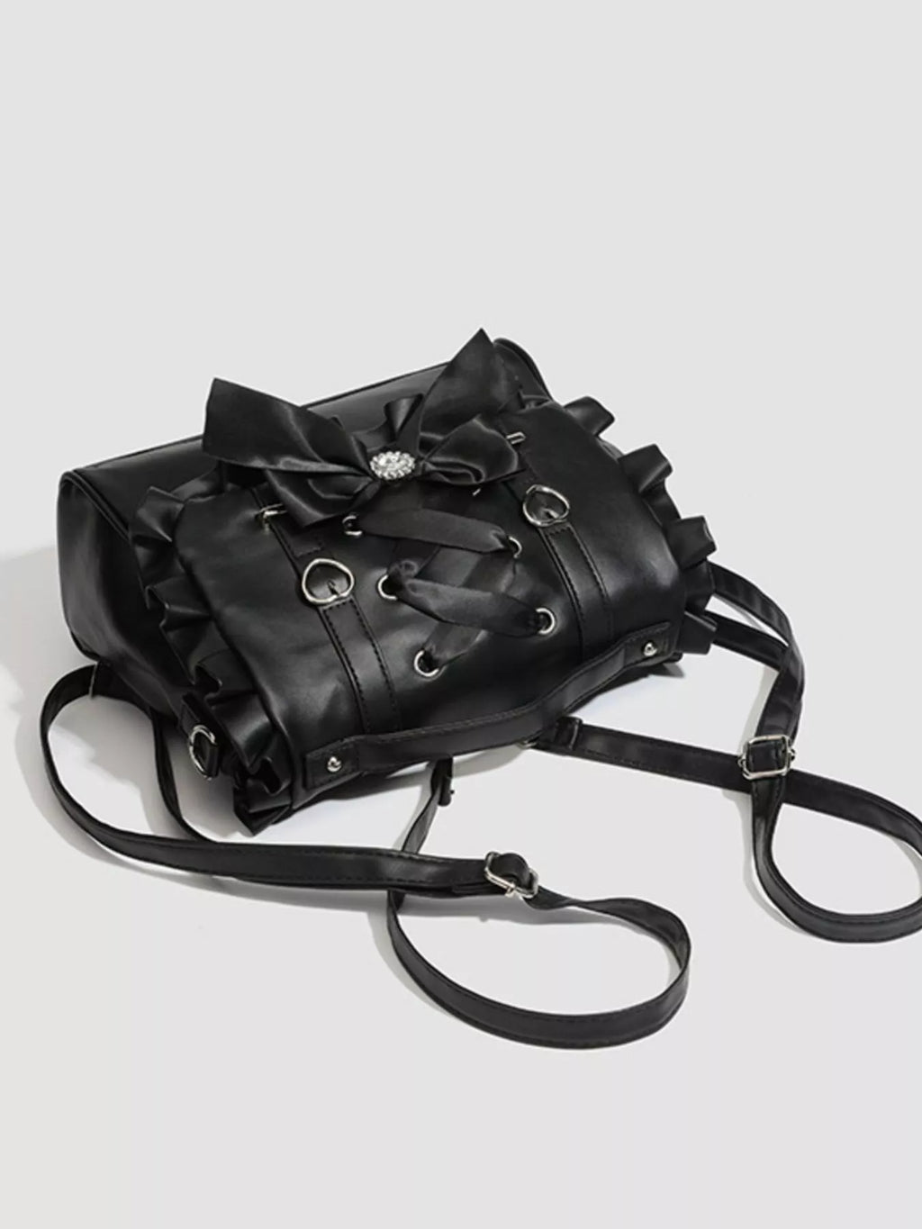 Black leather backpack with decorative bows on a light gray background