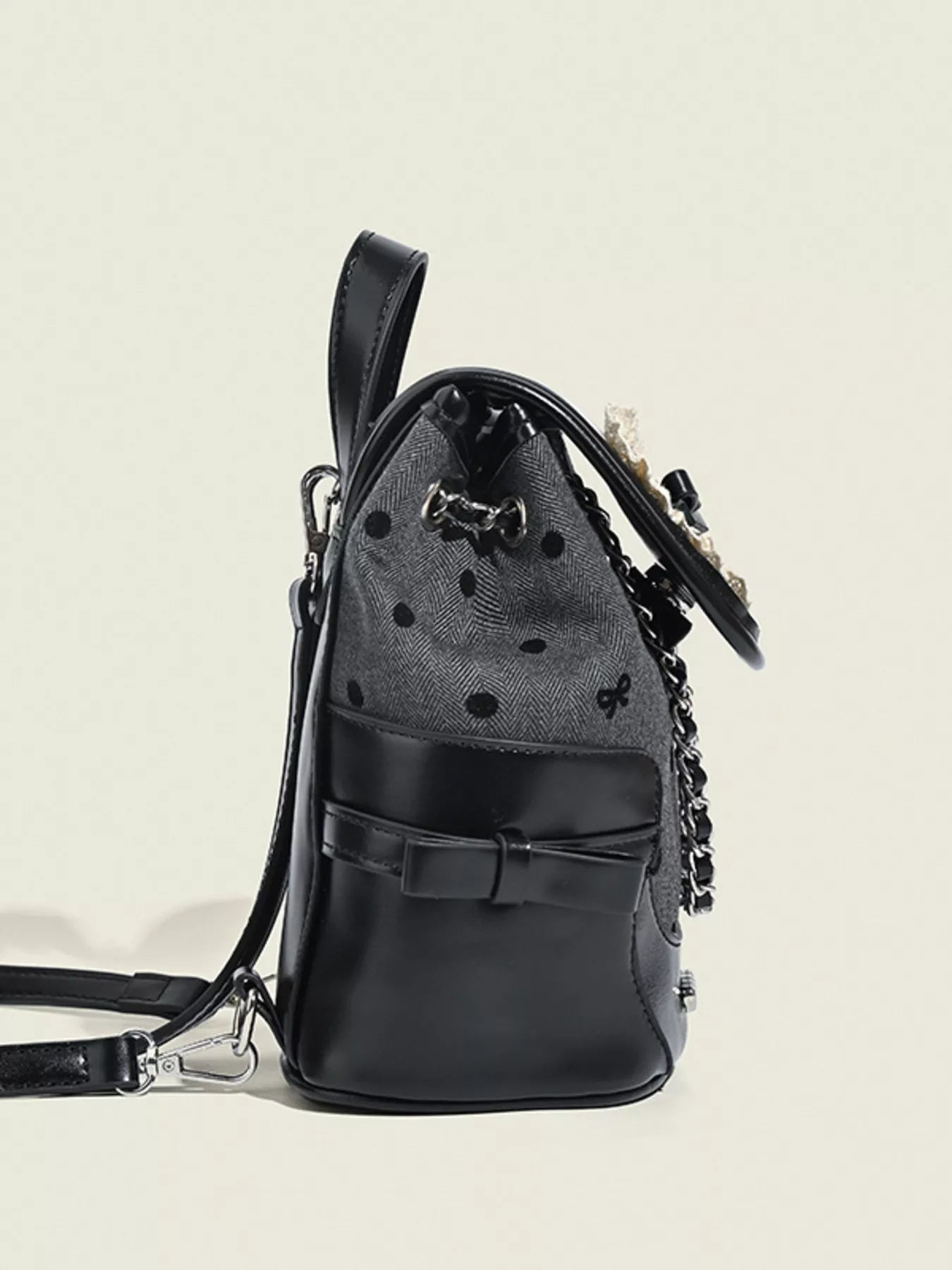 Black backpack with decorative chain on a beige background