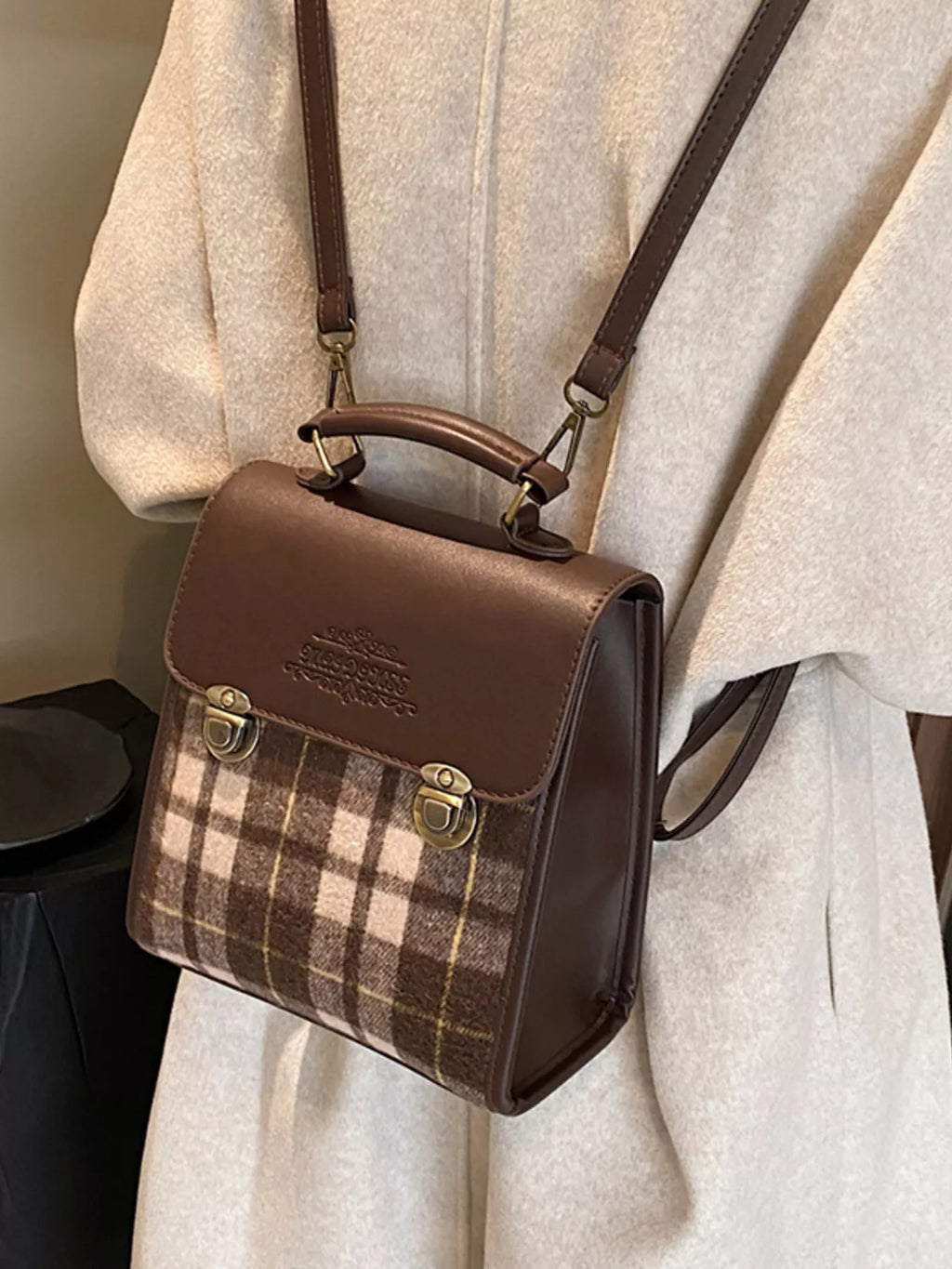 Brown plaid handbag with leather accents on a neutral background
