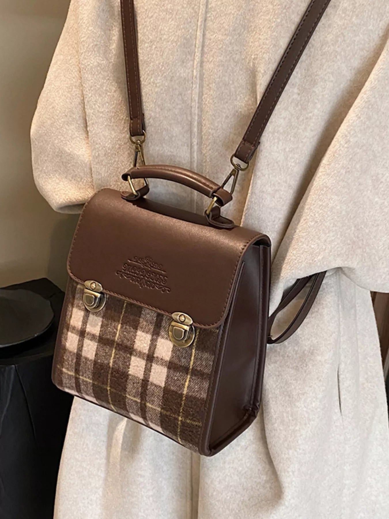 Brown plaid handbag with leather accents on a neutral background