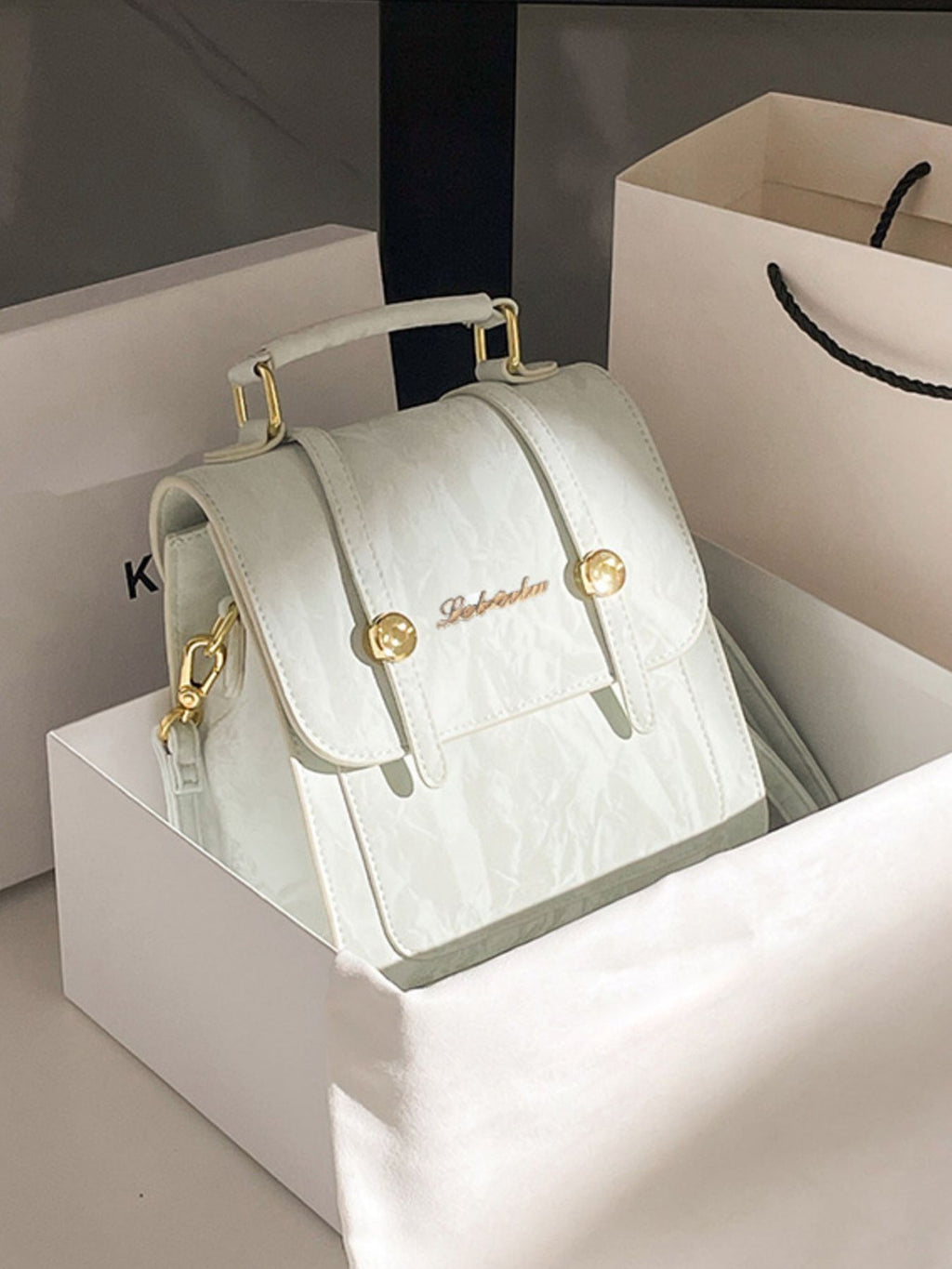 Light green handbag with gold accents on a white box