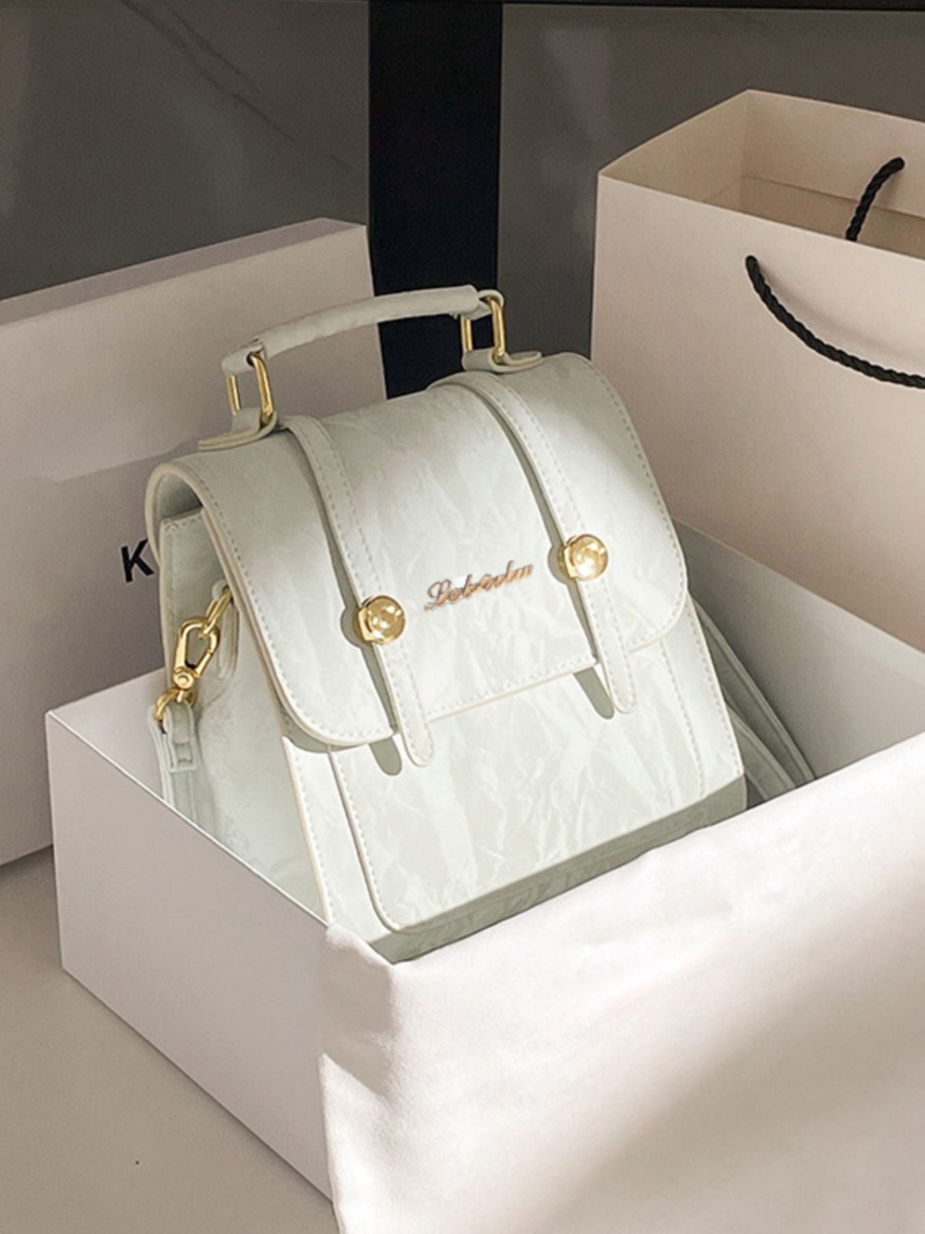Light green handbag with gold accents on a white box