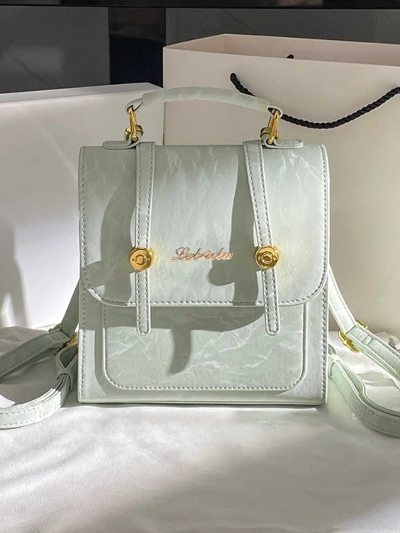 Light green handbag with gold accents on a white background