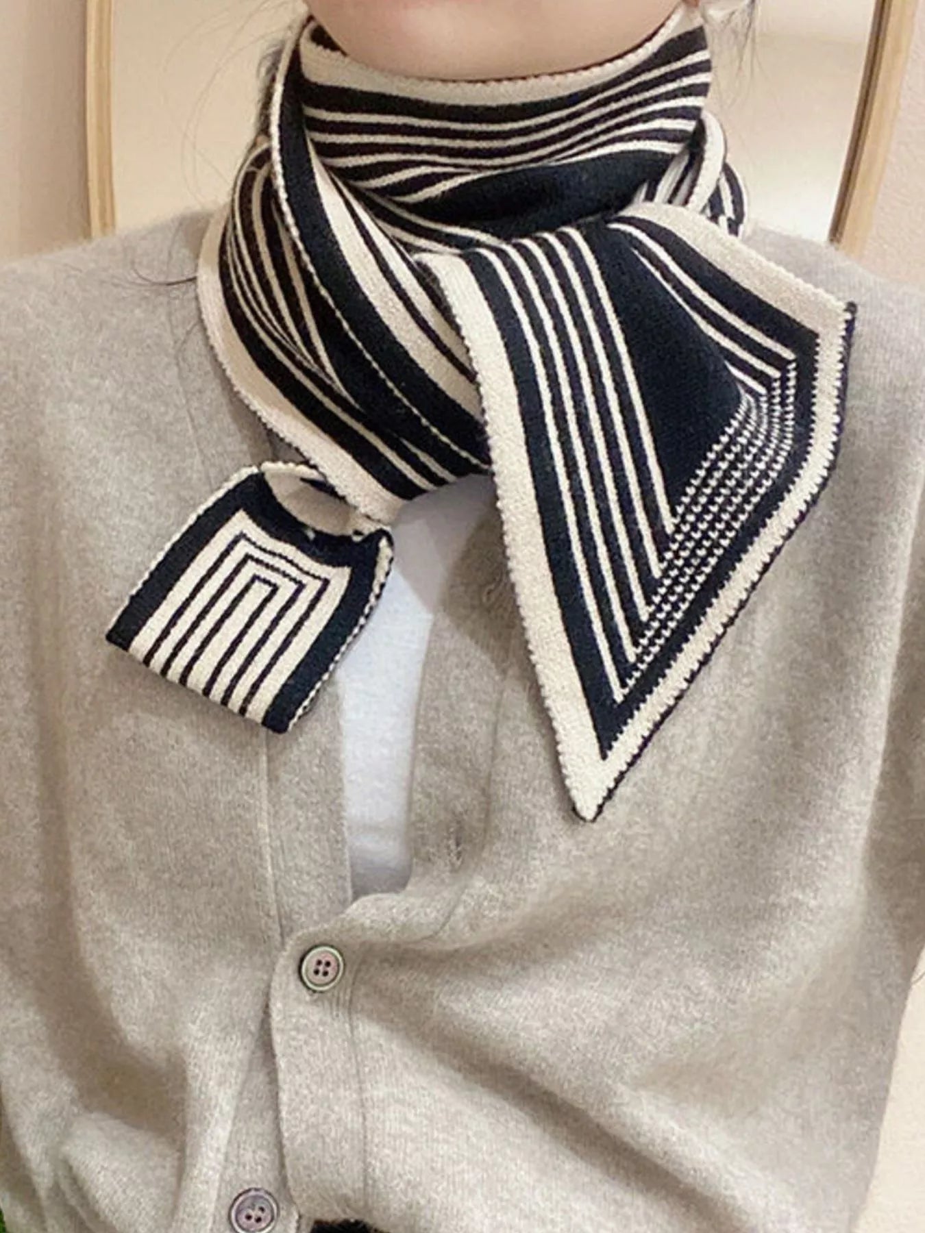 Mannequin wearing a gray cardigan with a black and white striped scarf and pocket square.