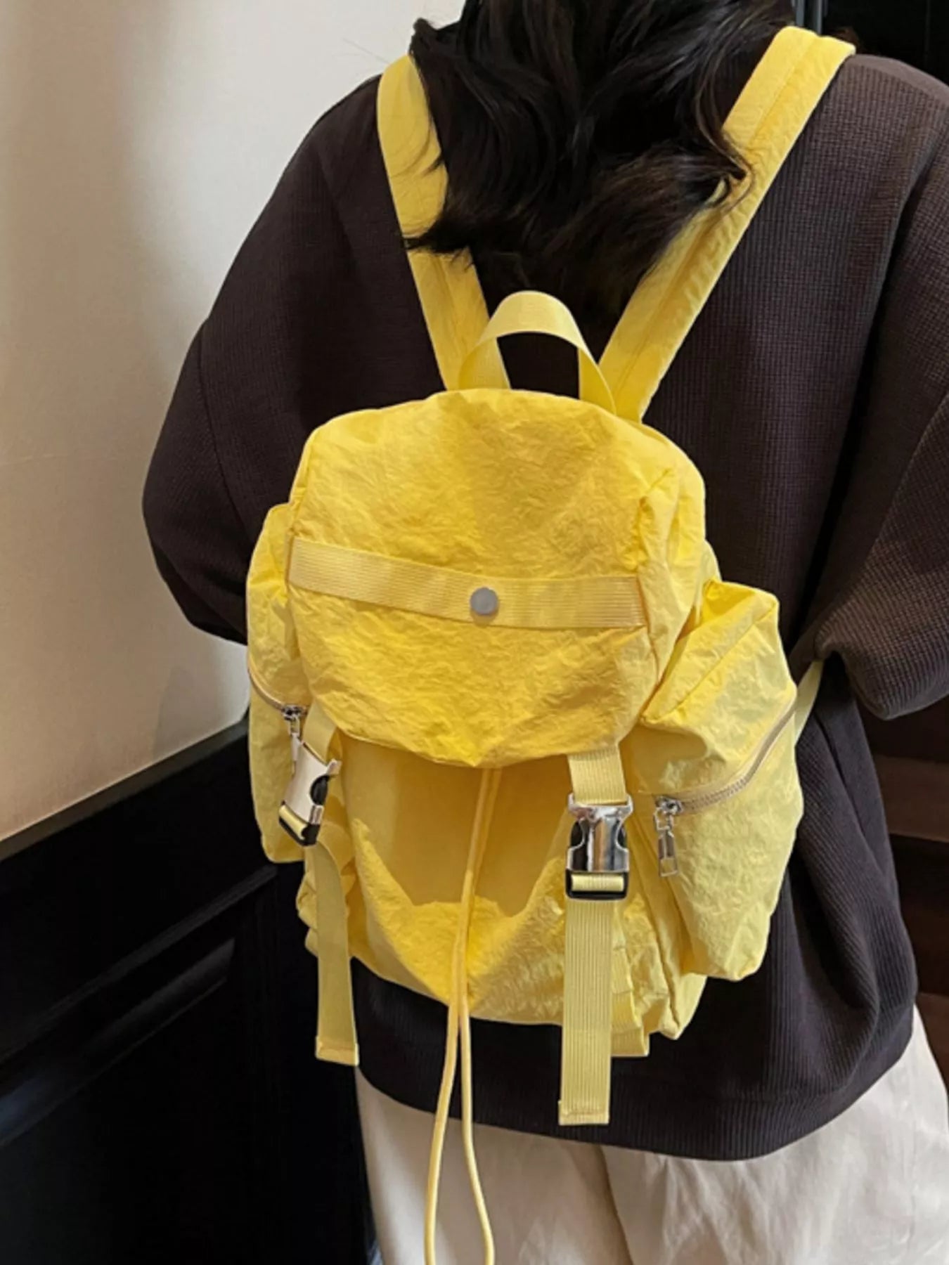Person wearing a yellow backpack with a plain background