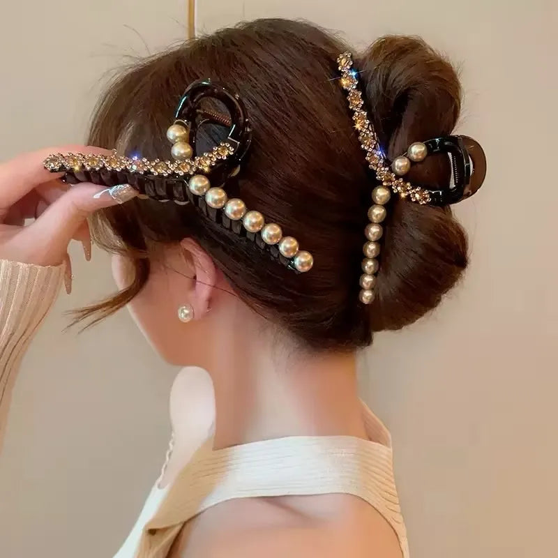 Woman with styled hair using a decorative hair clip with pearls against a neutral background