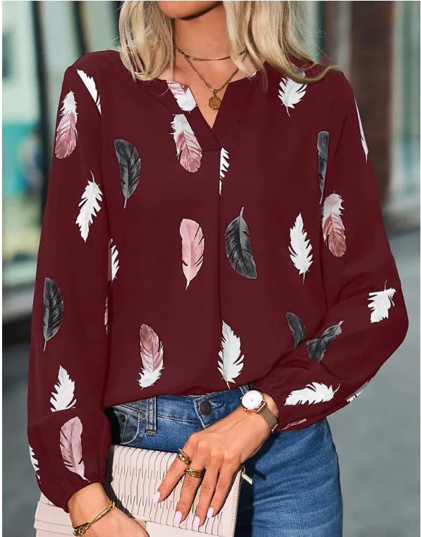 Maroon blouse with feather pattern worn by a person, blurred background