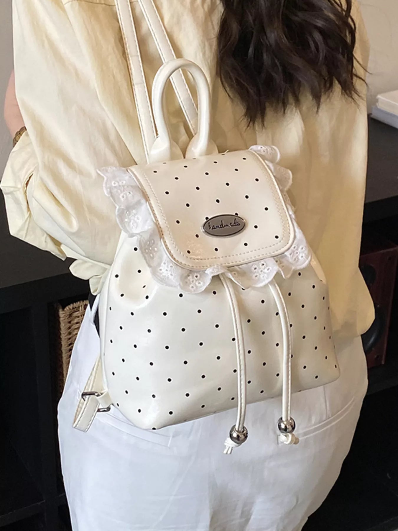 White polka dot backpack with lace details worn by a Model