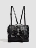 A black faux-leather shoulder bag with ruffled edges, dual shoulder straps, a large front bow, and heart-shaped metal details, shown on a light gray background.