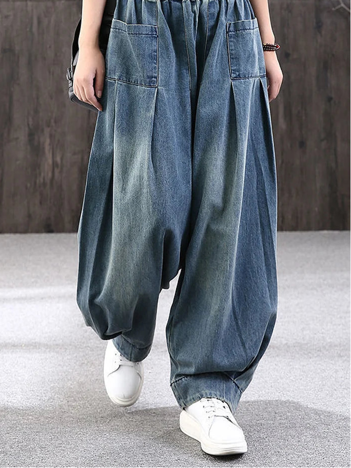 Model wearing blue denim harem pants with a blurred background