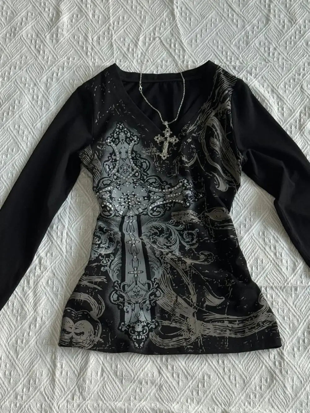 Black shirt with intricate silver design on a textured white background