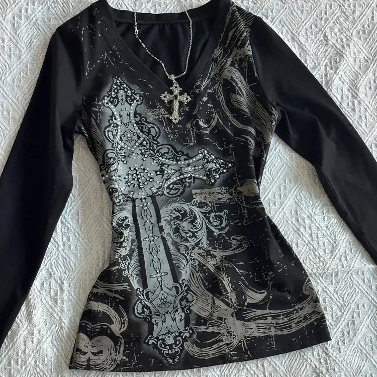 Black long-sleeve top with intricate white patterns on a textured white surface