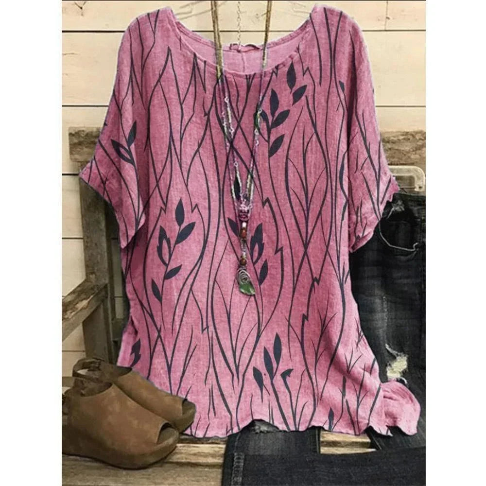 Pink blouse with black leaf pattern on a wooden surface