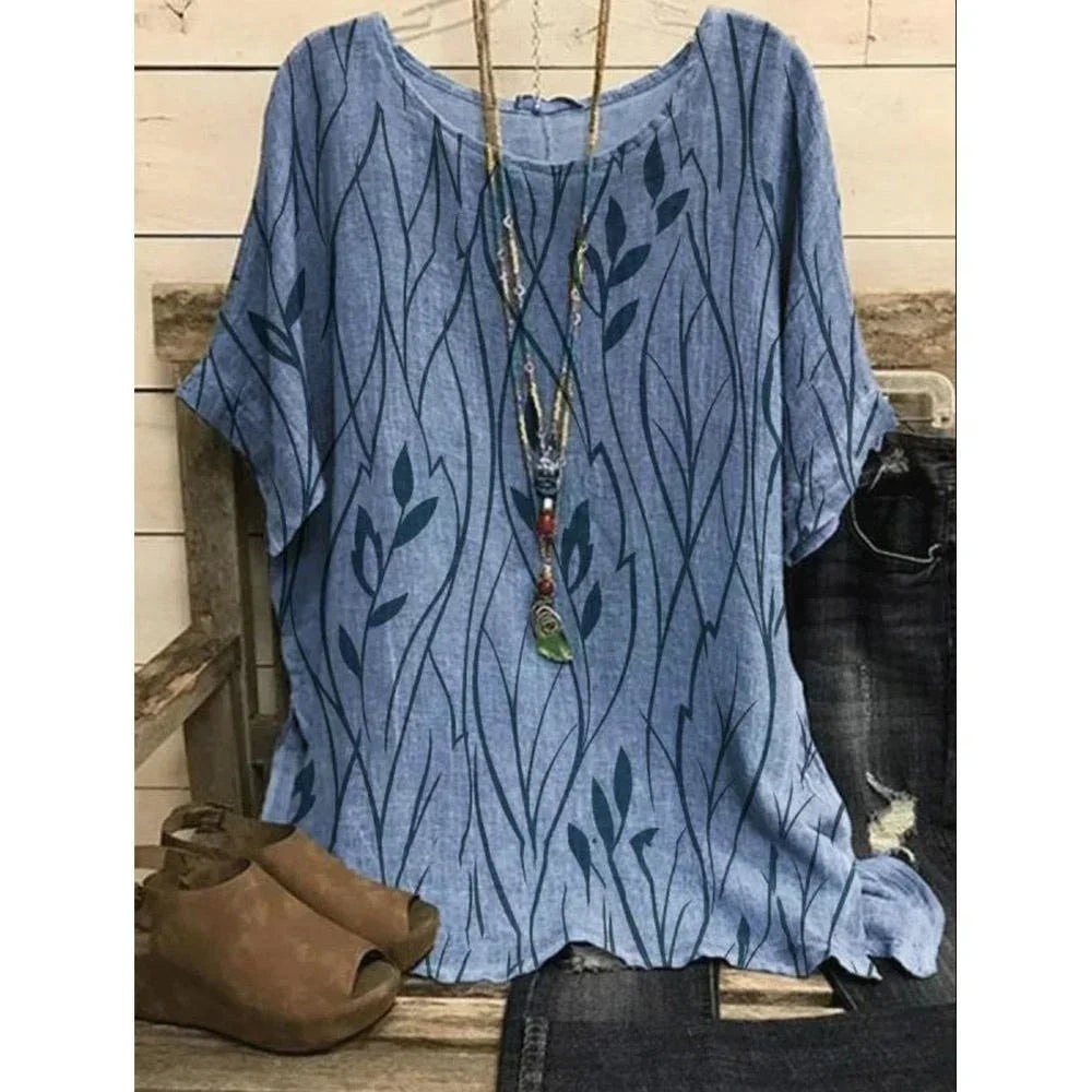Blue patterned shirt with a necklace and brown shoes on a wooden surface