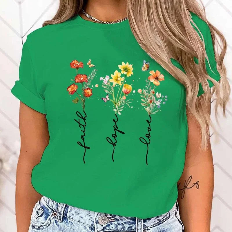 Green t-shirt with floral design and 'faith hope love' text worn by a person.
