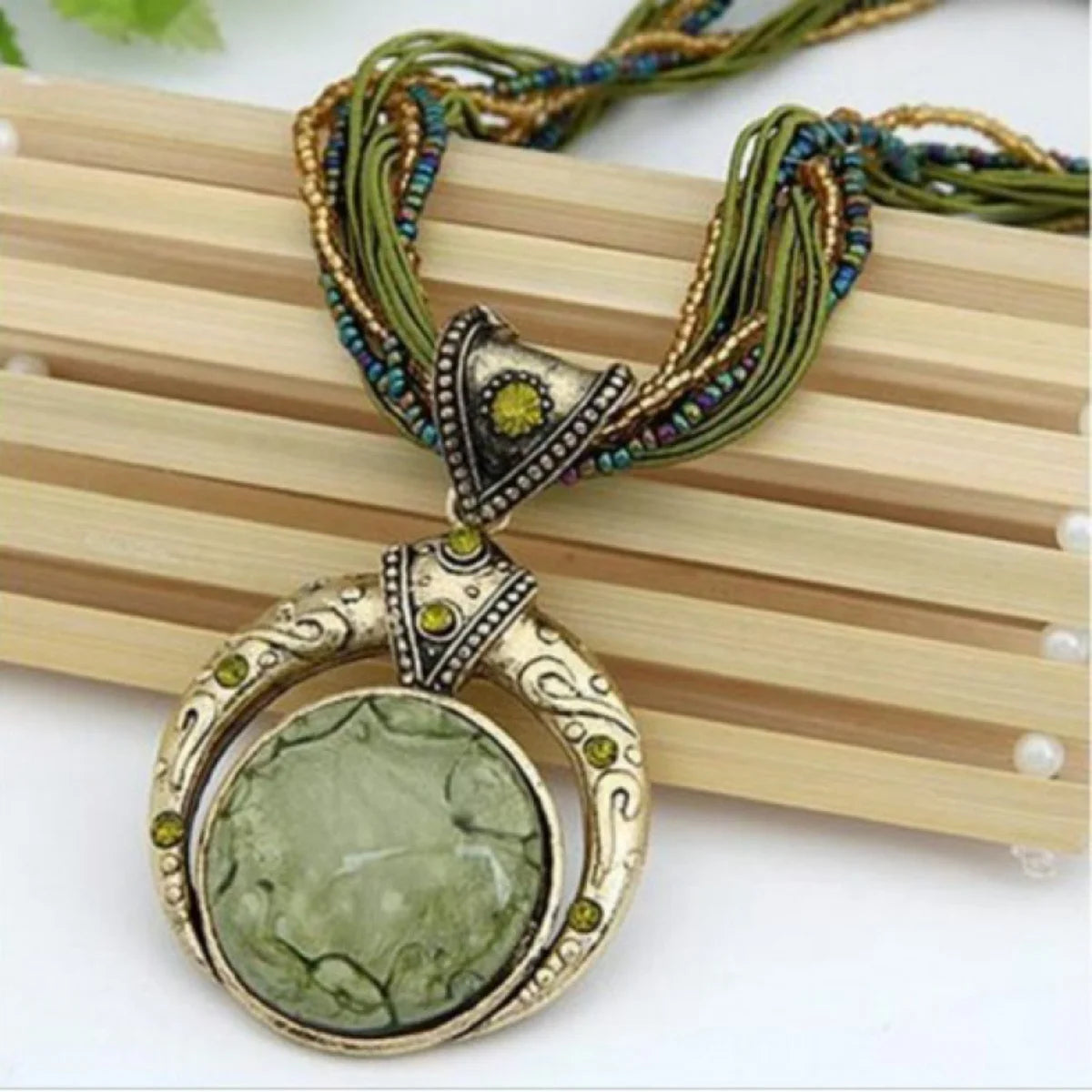 Vintage necklace with a green pendant on a wooden surface