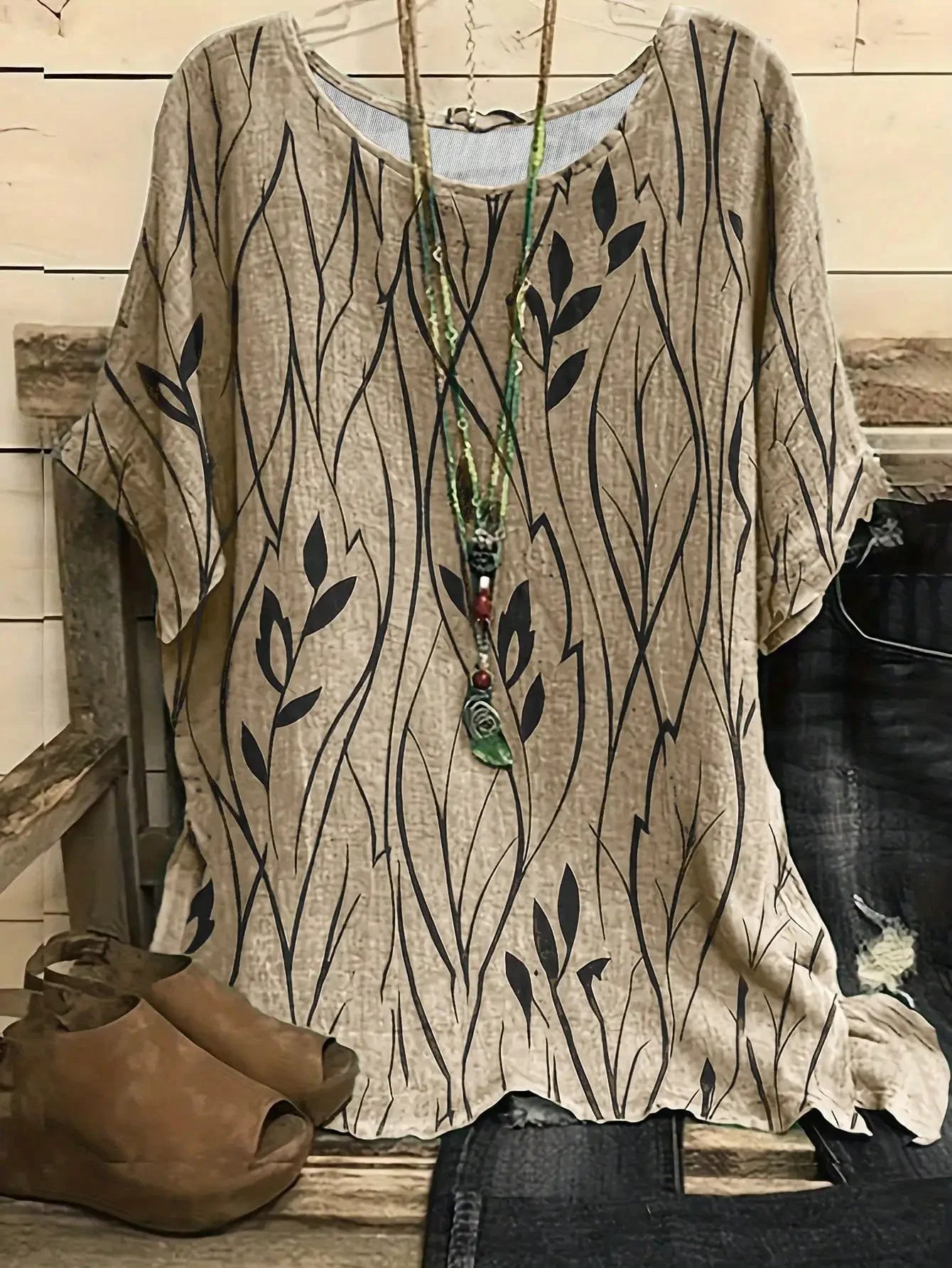 Beige tunic with leaf pattern on a wooden surface